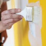 Painting with white paint over a yellow wall